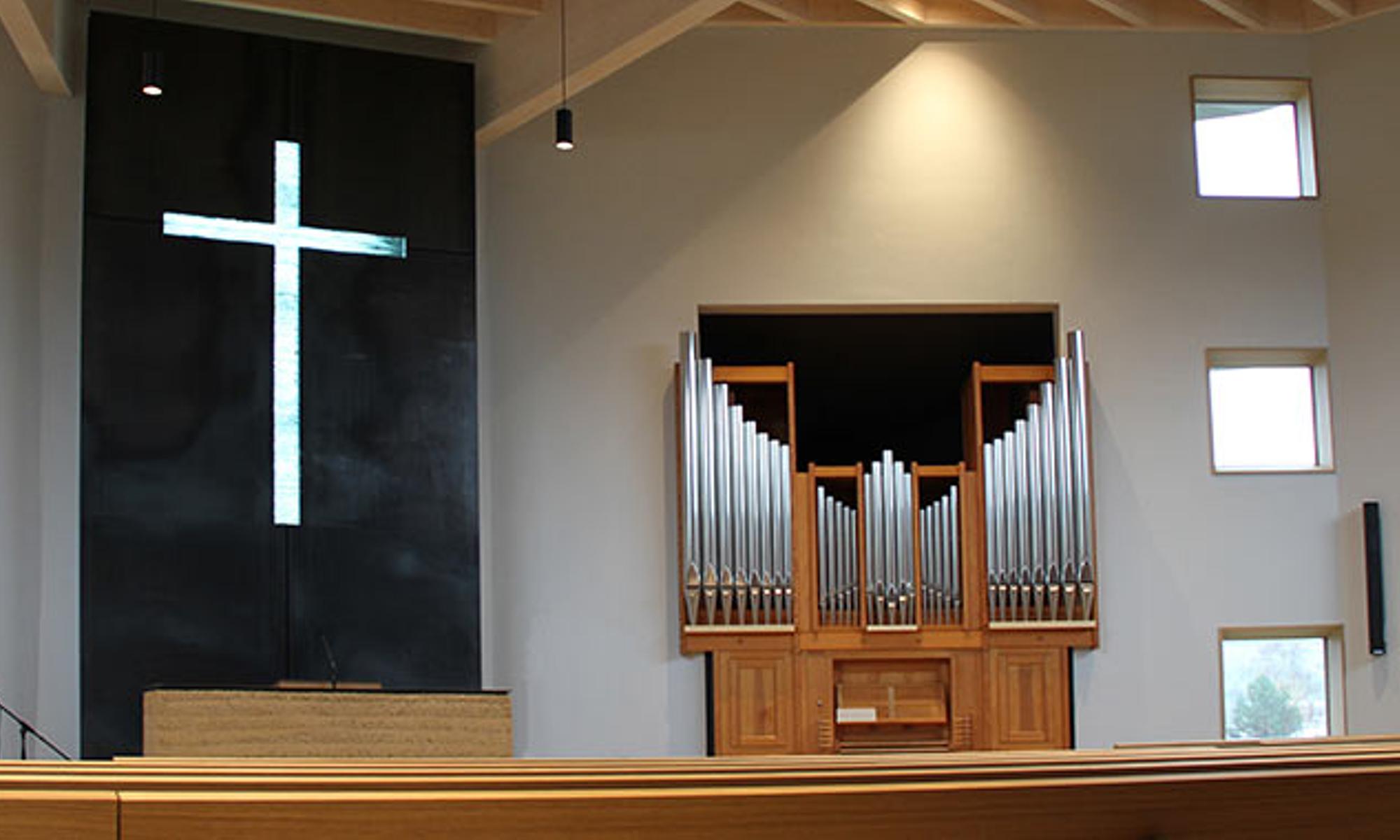 Blick auf den Altar mit dem durchscheinenden Kreuz aus Glasplatten und die Orgel