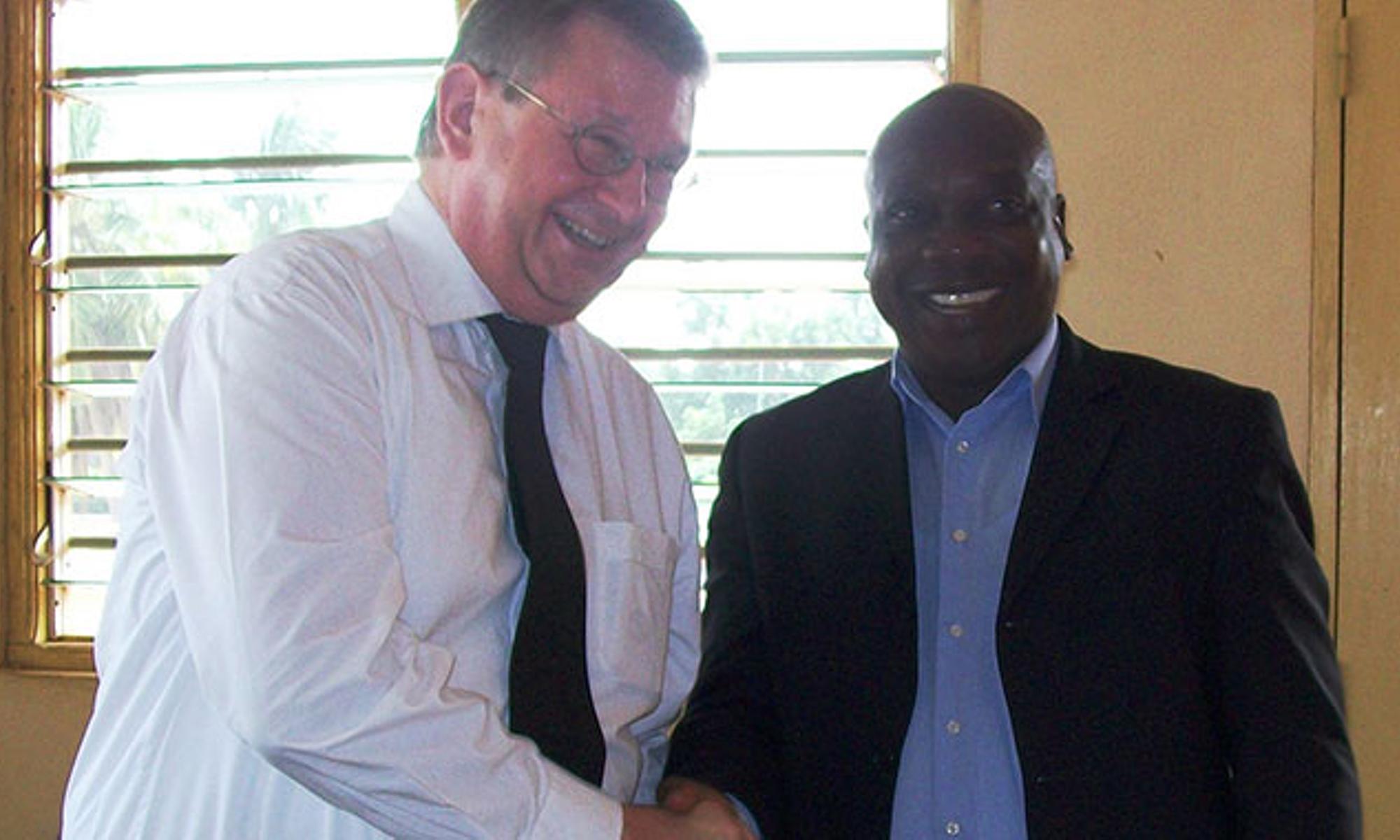 Apostel Herbert Bansbach (im Bild links) übergibt die Spende an die Hilfe-Organisation in Togo
